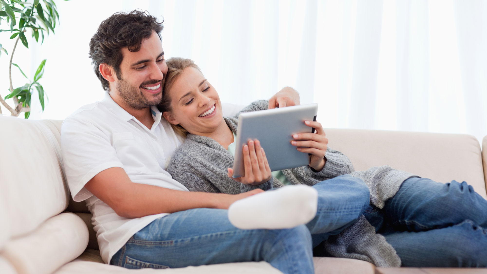 Couple sitting together on couch looking at laptop